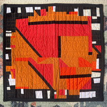 Load image into Gallery viewer, Geometric quilt with orange, red, and black patterns on a textured surface
