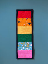 Load image into Gallery viewer, Colorful quilted strip with floral patterns on a blue background

