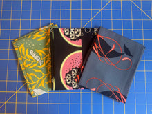 Load image into Gallery viewer, Three fabric swatches with different patterns on a blue grid background
