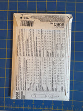 Load image into Gallery viewer, A sewing pattern envelope for Simplicity 8060 H5 is shown flat on a blue cutting mat with yellow grid lines.
