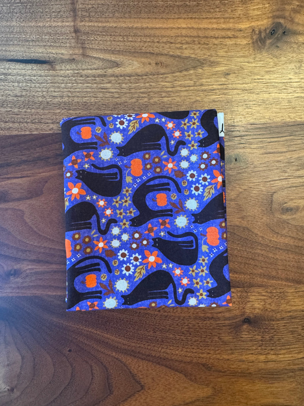 Colorful fabric with black cat pattern on a wooden surface
