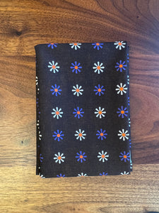Folded dark brown fabric with floral pattern on a wooden surface