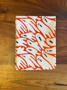 Fabric with orange and white ghost pattern on a wooden surface