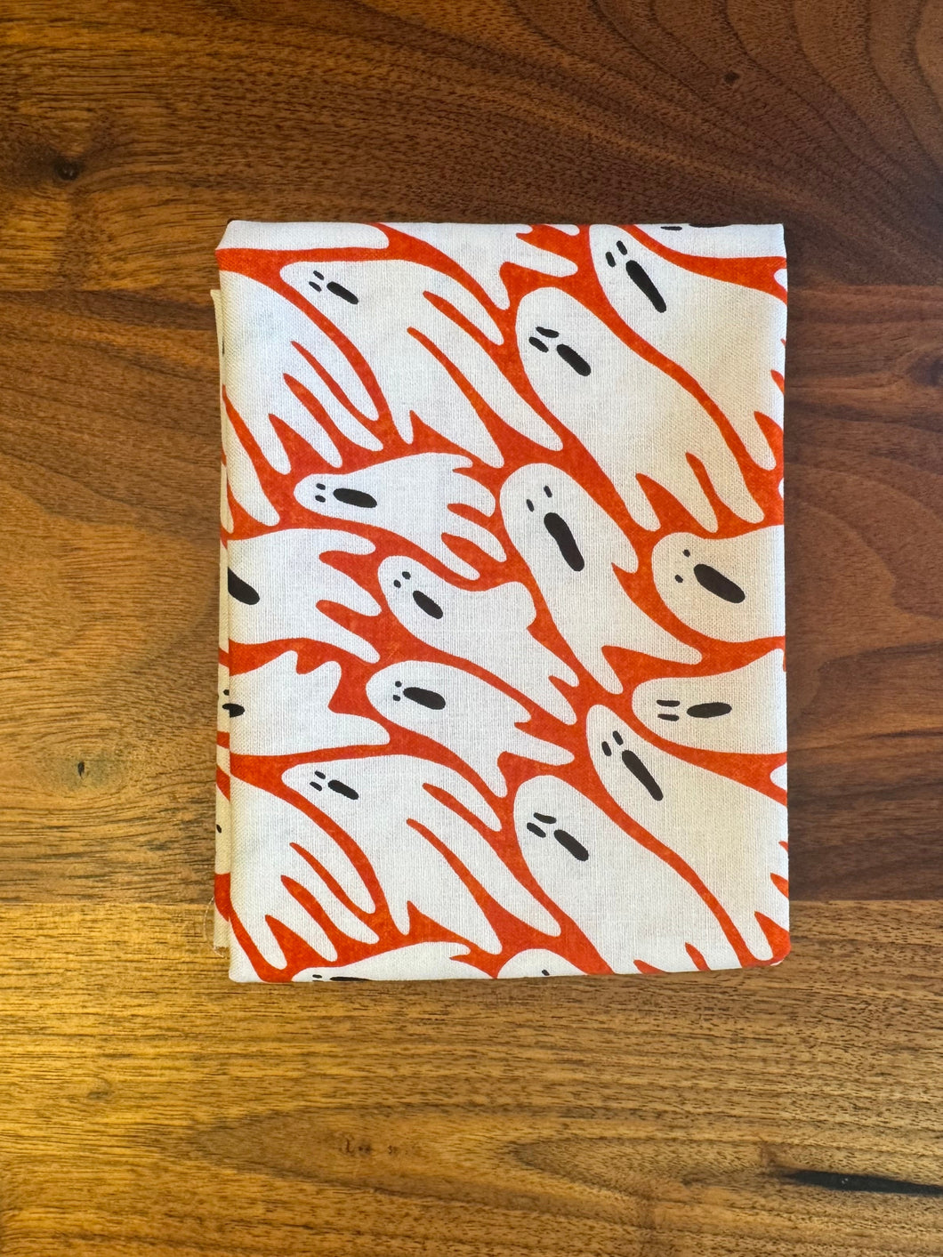 Fabric with orange and white ghost pattern on a wooden surface